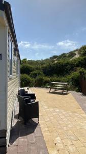 un patio con banco y mesa de picnic en Chalet Playa direct aan zee in IJmuiden, en IJmuiden