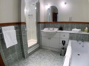 
a bathroom with a tub, sink and mirror at Ardno House B & B in Glencoe
