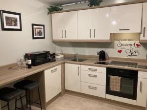 a kitchen with white cabinets and a sink and a microwave at Tailors Lodge, Luxurious peaceful Apartment- Castleisland, Kerry in Castleisland