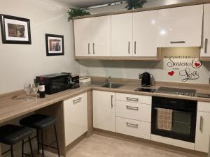 een keuken met witte kasten, een wastafel en een magnetron bij Tailors Lodge, Luxurious peaceful Apartment- Castleisland, Kerry in Castleisland