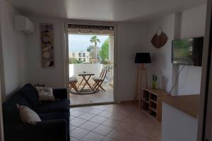 uma sala de estar com um sofá e vista para um pátio em Magnifique Studio à 50m de la plage de Cavaliere - Studio Tamarindo em Le Lavandou