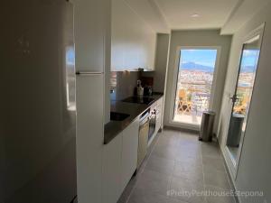 a kitchen with white cabinets and a view of a city at #PrettyPenthouseEstepona in Estepona