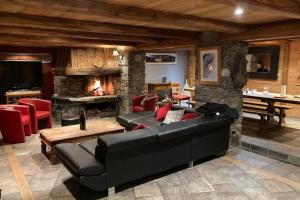 a living room with a black couch and a stone fireplace at Paisible chalet montagne avec option jacuzzi in Séez