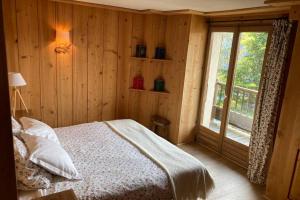 una camera da letto con pareti in legno e un letto con finestra di Paisible chalet montagne avec option jacuzzi a Séez