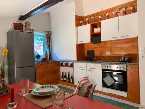 a kitchen with white cabinets and a table and a refrigerator at Schwalbennest Velden in Velden am Wörthersee