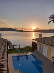 a house with a swimming pool next to a body of water at Girassóis da Lagoa - Guesthouse in Florianópolis