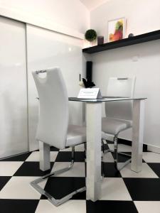 a glass table and two white chairs in a room at Black and White Studio in Ljubljana