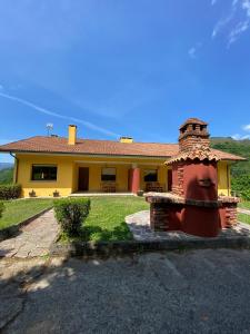 a yellow house with a brick chimney in front of it at Finca La Cuesta in Cangas de Onís