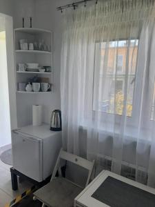 サンドミエシュにあるNoclegi na Kazimierzaの白いカーテンと椅子付きの窓が備わる客室です。
