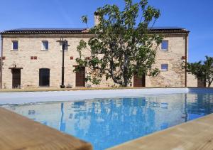an empty swimming pool in front of a brick building at SelvaGiurata Farmhouse Villa in San Benedetto del Tronto