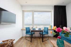 a dining room with a table and chairs and a window at Costa in Zandvoort