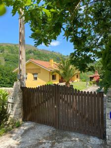 a wooden fence in front of a yellow house at Finca La Cuesta in Cangas de Onís