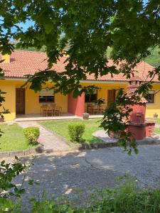 a yellow building with tables and chairs in front of it at Finca La Cuesta in Cangas de Onís