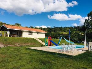 a pool with a slide and chairs in a yard at Sítio Santo Agostinho in Porangaba