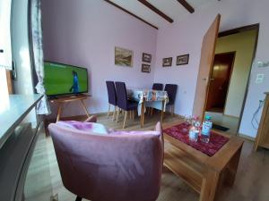 a living room with a chair and a table and a television at Ferienhaus Chalet Cottage Ourtalblick 2km von Vianden-Lux in Roth