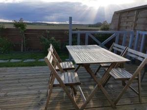 einen Picknicktisch aus Holz und zwei Stühle auf einer Terrasse in der Unterkunft GITE LES AILES DU VENT- BUIGNY ST MACLOU in Buigny-Saint-Maclou