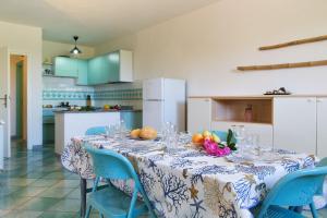 a kitchen with a table with blue chairs and a table cloth at Acqua Marina in Monte Petrosu