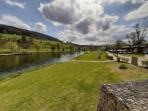 a river with a grassy field next to a body of water at Ferienhaus Chalet Cottage Ourtalblick 2km von Vianden-Lux in Roth