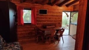 a dining room with a table and chairs in a log cabin at Etna Rural Cottage with Jacuzzi in Pedara