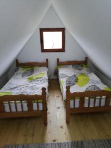 2 łóżka w pokoju na poddaszu z oknem w obiekcie Golija Vikend kuća Milenković w mieście Raška