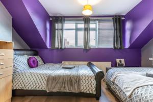 a purple bedroom with a bed and a window at City centre super spacious apartments free parking and wi fi in Newcastle upon Tyne