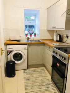 a kitchen with a sink and a washing machine at Whiteley's Cottages in Dumbarton
