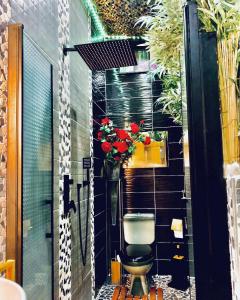 a bathroom with a toilet and a vase of flowers at Jungle Vibes - Jacuzzi - Sauna in Yerres