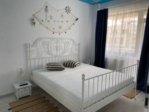 a white bed in a white bedroom with a window at Ela's Apartment in Mamaia Sat/Năvodari
