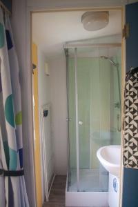 La salle de bains est pourvue d'une douche en verre et d'un lavabo. dans l'établissement Mobil Home - 4 personnes, à Saint-Martin-Plage