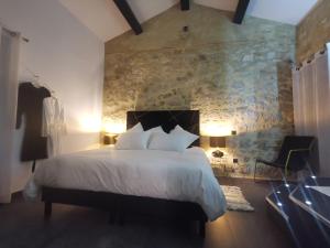 um quarto com uma cama grande e uma parede de pedra em Le Domaine du Grand Cru em Vagnas