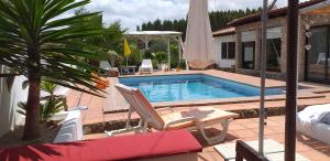 a swimming pool with two chairs and a umbrella at Casa Uldina in Bombarral