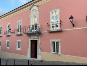 un edificio rosa con balcones en un lateral en Travassos 11 en Elvas