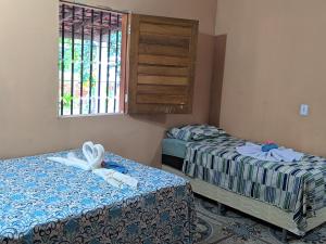 a room with two beds and a window at Chalé Cantinho Meu in Barreirinhas