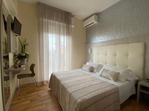 a bedroom with a large white bed and a window at Hotel Jumbo in Rimini