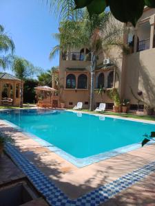 une grande piscine en face d'une maison dans l'établissement Les Jardins de Ryad Bahia, à Meknès
