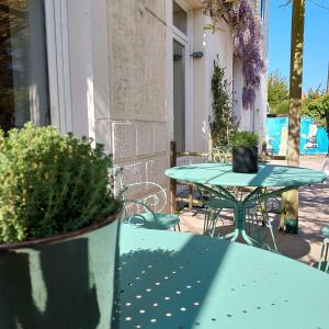 a green table and chairs on a patio at Maison Triton et Porcelaine in Saint-Coulomb