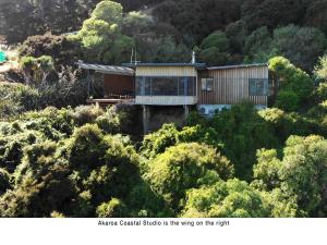 Akaroa Coastal Studio في أكارو: منزل على قمة تل به اشجار