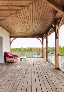 a wooden deck with a couch and a table at La Découverte, Jacuzzi, Sauna, et Terrasse avec vue sur lac à la campagne entre Toulouse et Auch in Catonvielle