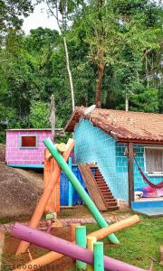 Um edifício azul com um monte de pauzinhos coloridos à frente. em Chale Cantão de Itamambuca em Ubatuba