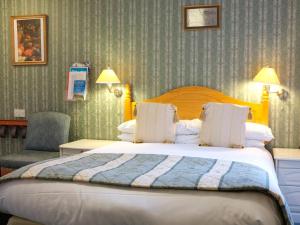 een hotelkamer met een groot bed en een stoel bij The Well House in Pitlochry