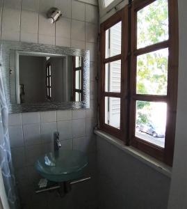 uma casa de banho com um lavatório de vidro e um espelho. em 515 St. Patrick Guesthouse Hotel em Buenos Aires