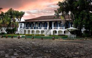 un gran edificio blanco con palmeras delante en Hotel Fazenda Villa-Forte en Engenheiro Passos