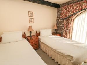 two beds in a room with a window at Pansy Plot in Wooler