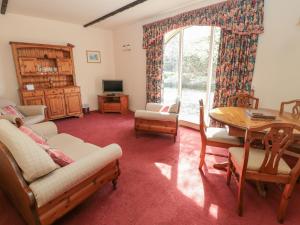 een woonkamer met een tafel en stoelen en een raam bij Cherryburn Cottage in Wooler