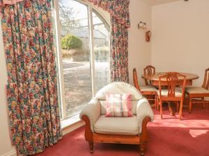 een woonkamer met een stoel en een raam bij Cherryburn Cottage in Wooler