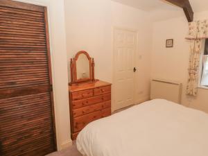 a bedroom with a bed and a mirror and a dresser at The Smithy in Wooler
