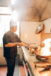 un homme dans une cuisine préparant de la nourriture sur une cuisinière dans l'établissement Diamond Hotel Thai Binh, à Thái Bình