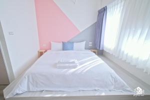 1 dormitorio con cama blanca y ventana en Jezreel Inn, en Kaohsiung