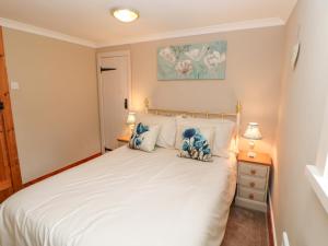 1 dormitorio con 1 cama blanca y 2 lámparas en Shepherd's Cottage en Newbiggin