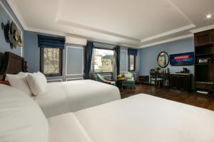 a bedroom with two white beds and a living room at Romantique Hotel De Hanoi in Hanoi